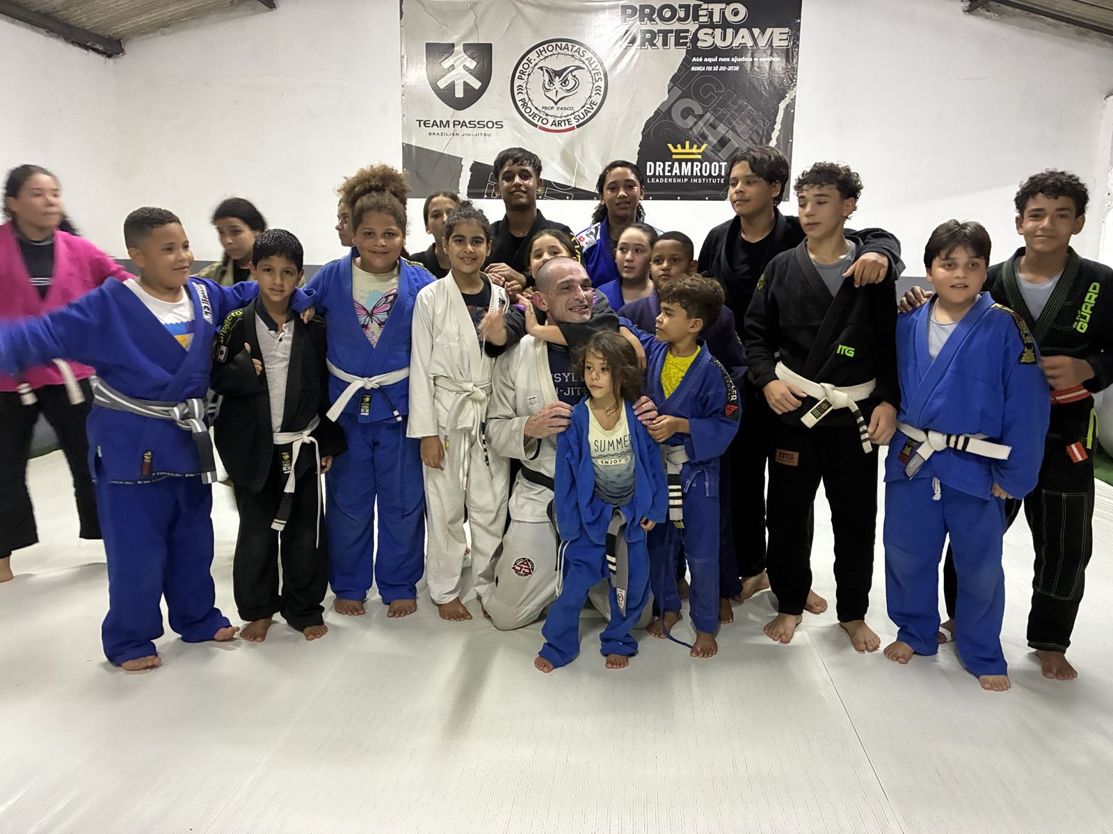 Kids from Projeto Arte Suave gathered around a coach on the mat