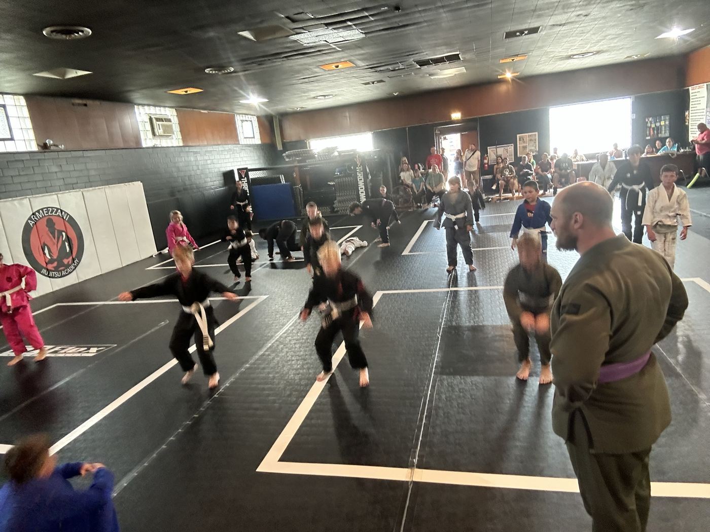 Kids class drilling across the mats with their coach